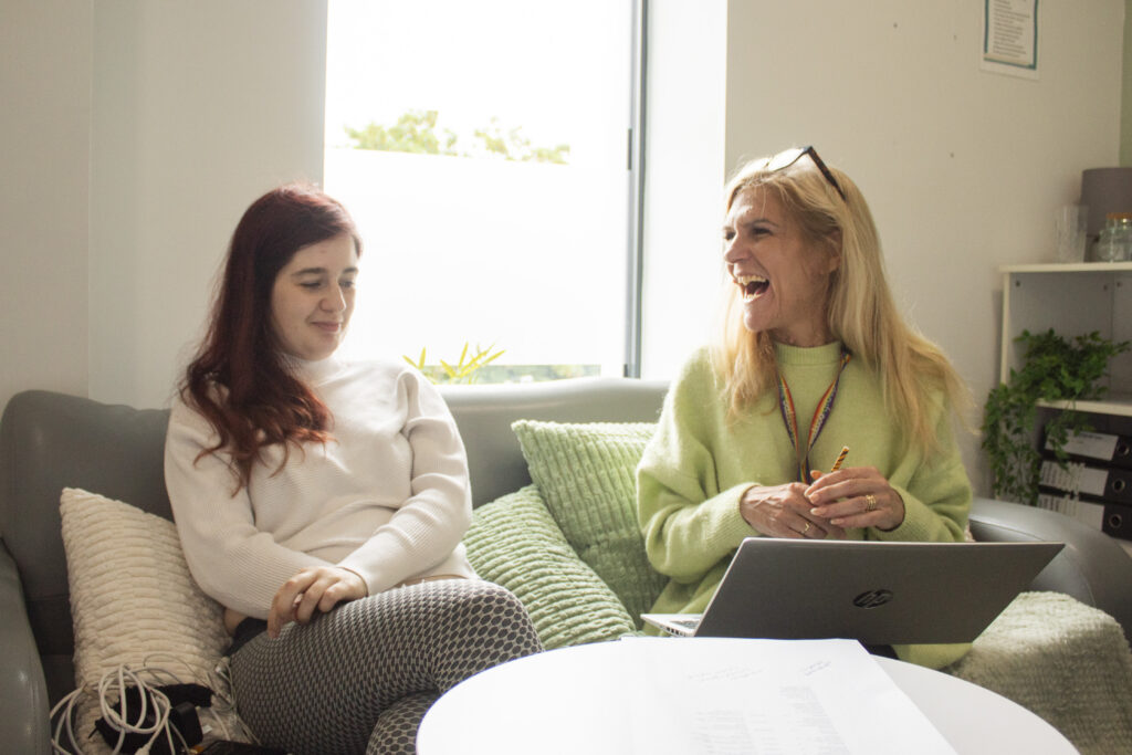 Housing support worker and resident sitting together in a private meeting area with a laptop during a support session in Lancashire.